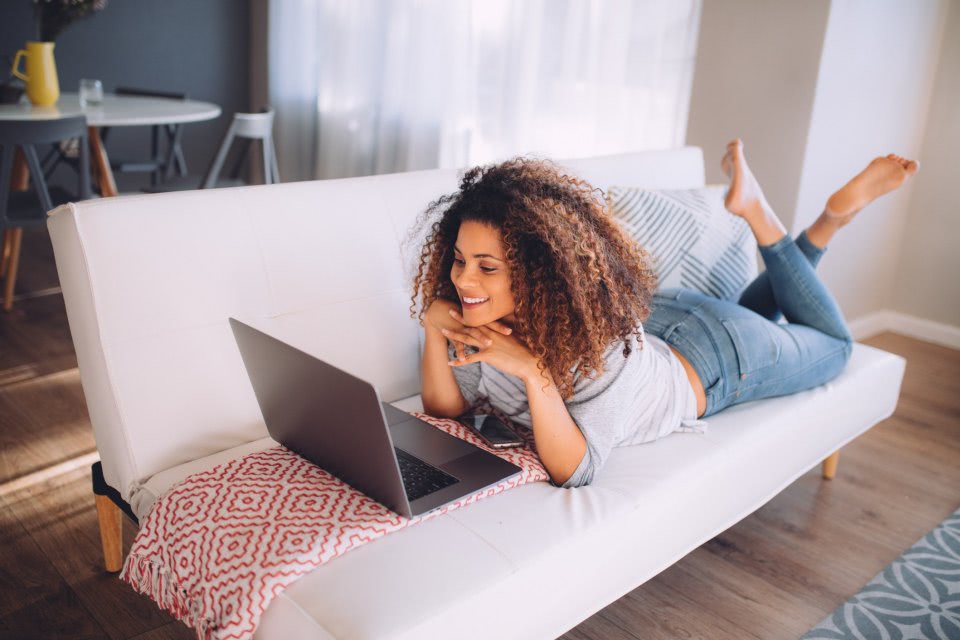 młoda kobieta leży na sofie i kupuje meble przez internet